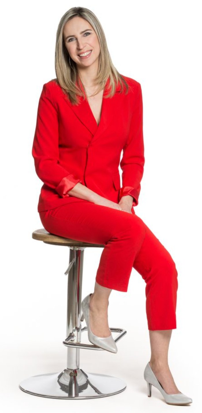 Maud Berthelot en tailleur rouge, assise sur un tabouret